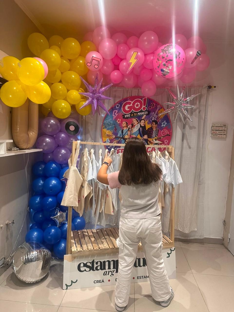Una invitada eligiendo su remera en el perchero del stand